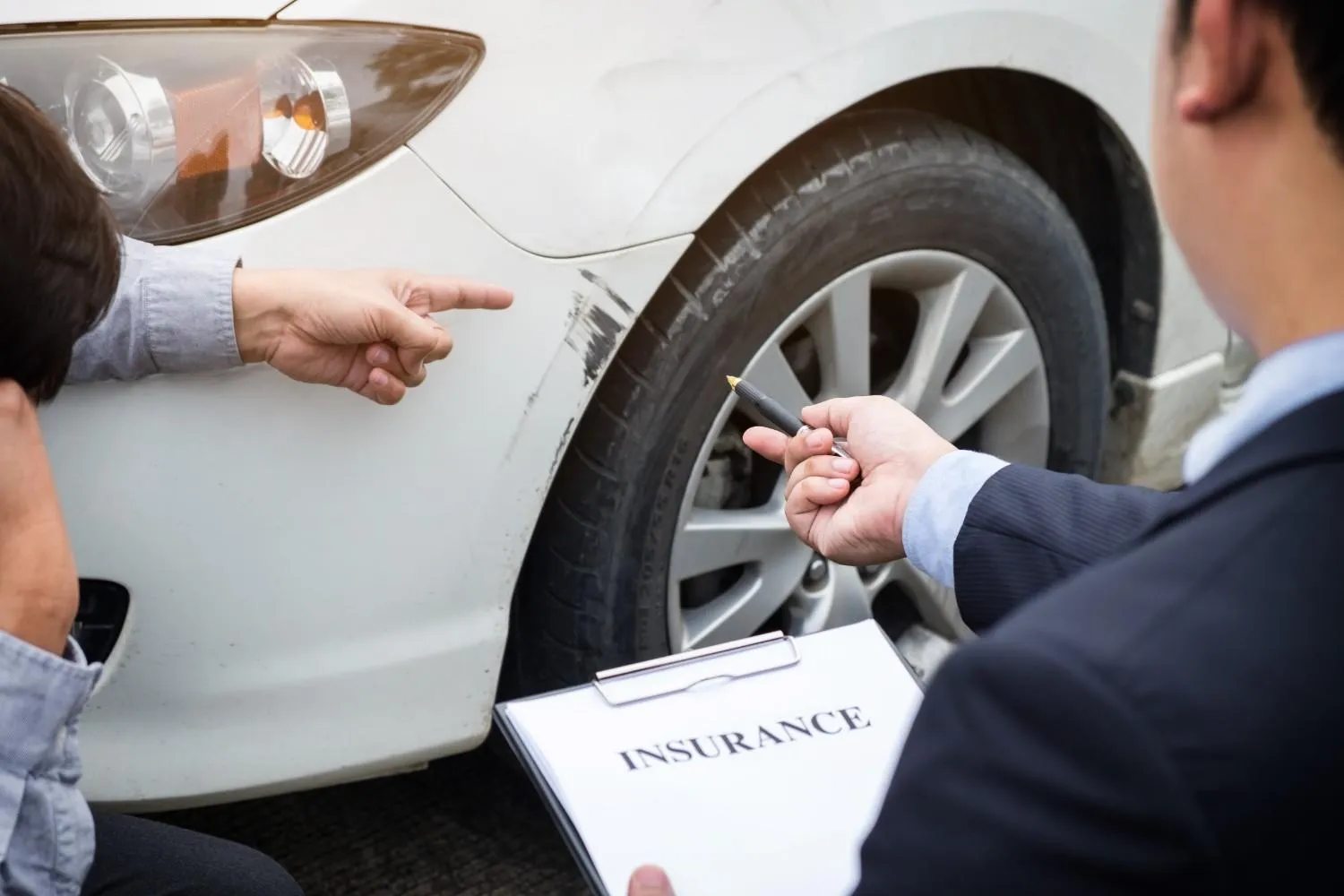 Scratched car fender being checked against an insurance form